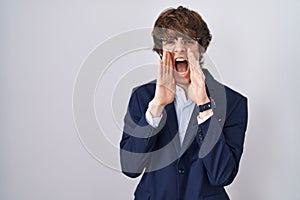 Hispanic business young man wearing glasses shouting angry out loud with hands over mouth