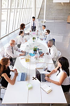 Hispanic Businessman Leading Meeting At Boardroom Table