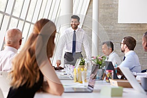 Hispanic Businessman Leading Meeting At Boardroom Table