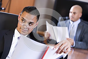 Hispanic businessmen in boardroom reviewing report