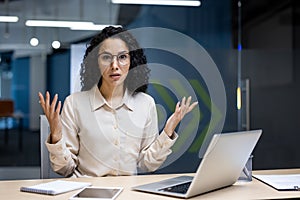 Hispanic businesswoman gesturing confusion at her desk