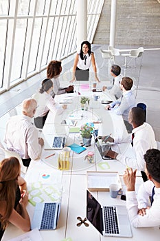 Hispanic Businesswoman Leading Meeting At Boardroom Table