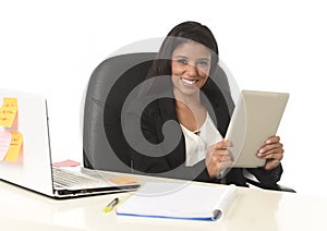 Hispanic businesswoman sitting at office computer desk smiling happy using digital tablet