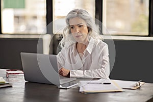 Hispanic Businesswoman Using Laptop Managing Budgets Online In Modern Office
