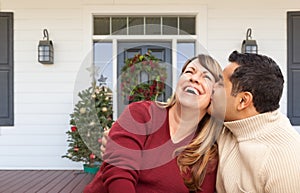 Hispanic and Caucasian Young Adult Couple On Christmas Decorated Front Porch of House