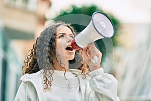 Hispanic child girl shouting angry using megaphone at the city
