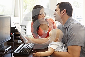 Hispanic couple and baby in home office