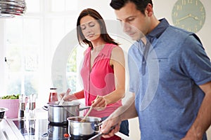 Hispanic Couple Cooking Meal At Home