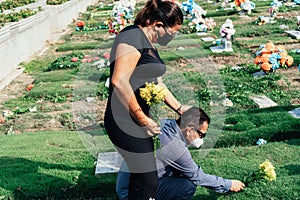 Hispanic Couple with protective mask bidding their last farewell to a relative in the cemetery. Coronavirus epidemic