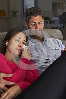 Hispanic Couple On Sofa Watching Sad Movie On TV