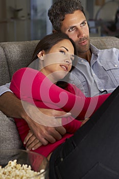 Hispanic Couple On Sofa Watching TV And Eating Popcorn