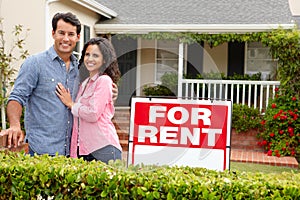 Hispanic couple standing outside home for rent