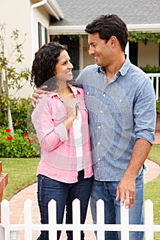 Hispanic couple standing outside new home