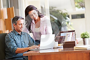 Hispanic Couple Using Laptop On Desk At Home