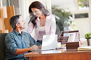 Hispanic Couple Using Laptop On Desk At Home