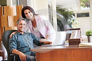 Hispanic Couple Using Laptop On Desk At Home