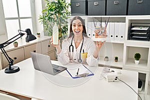 Hispanic doctor woman holding model of human anatomical skin and hair celebrating crazy and amazed for success with open eyes photo