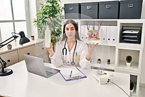 Hispanic doctor woman holding model of human anatomical skin and hair relaxed with serious expression on face photo