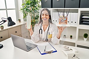 Hispanic doctor woman holding model of human anatomical skin and hair winking looking at the camera with sexy expression, cheerful photo