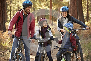 Hispanic family on bikes in a forest looking at each other