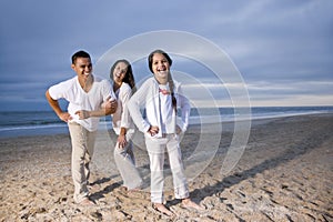 Hispanic family with daughter having fun on beach