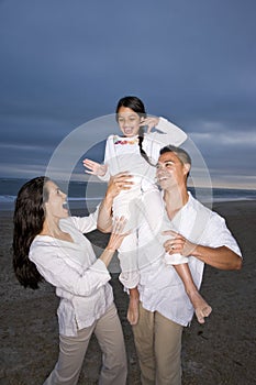 Hispanic family with daughter having fun on beach