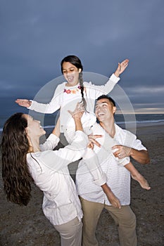 Hispanic family with daughter having fun on beach