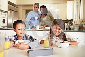 Hispanic Family Eating Breakfast Using Digital Devices