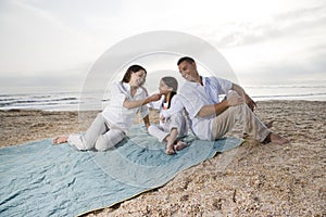 Hispanic family with little girl on beach blanket