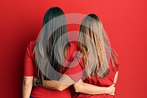 Hispanic family of mother and daughter wearing casual clothes over red background hugging oneself happy and positive from