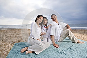 Hispanic family sitting on blanket at beach