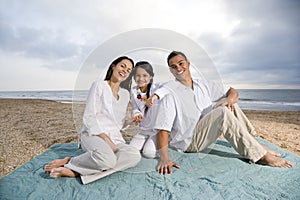 Hispanic family sitting on blanket at beach