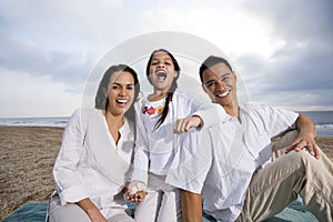 Hispanic family sitting on blanket at beach