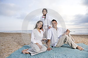 Hispanic family sitting on blanket at beach