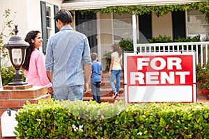 Hispanic family standing outside home for rent