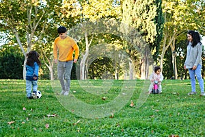 Hispanic family with two children playing soccer and with balance bike.