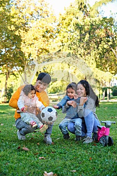 Hispanic family with two children soccer ball and balance bike in a park.