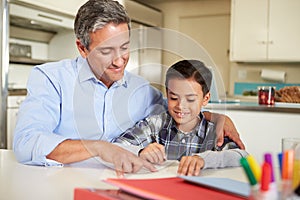 Hispanic Father Helping Son With Homework At Table