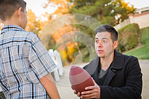 Hispanic Father Holding Football Teaching Young Boy