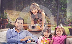 Hispanic father sitting in sofa with two daughters