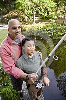Hispanic father and son fishing in pond