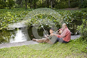 Hispanic father and son fishing in pond