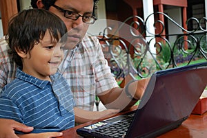 Hispanic father and son on laptop
