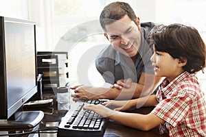 Hispanic father and son using computer at home