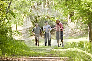 Hispanic father and sons hiking on trail in woods