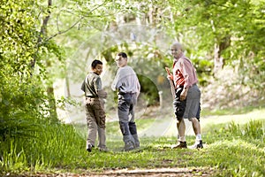 Hispanic father and sons hiking on trail in woods photo