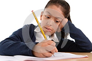 Hispanic female child writing carefully homework with pencil with concentrated face