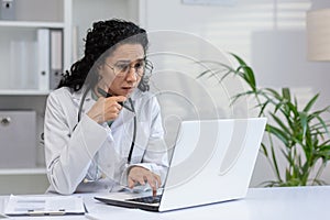 Hispanic female doctor working at her laptop in clinic