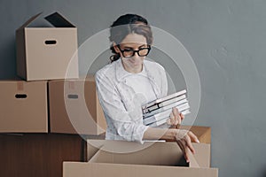 Hispanic female packing items in carton box on relocation day. Moving, renovation, mortgage concept