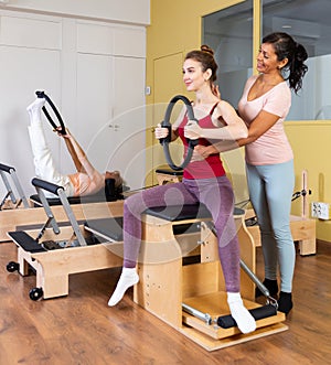 Hispanic female trainer controlling girl exercising with pilates ring